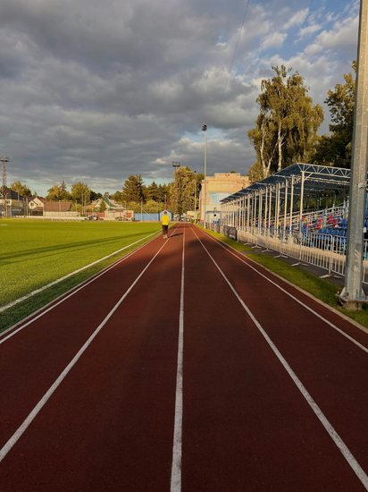 A lone athlete on a running track under a cold, overcast sky